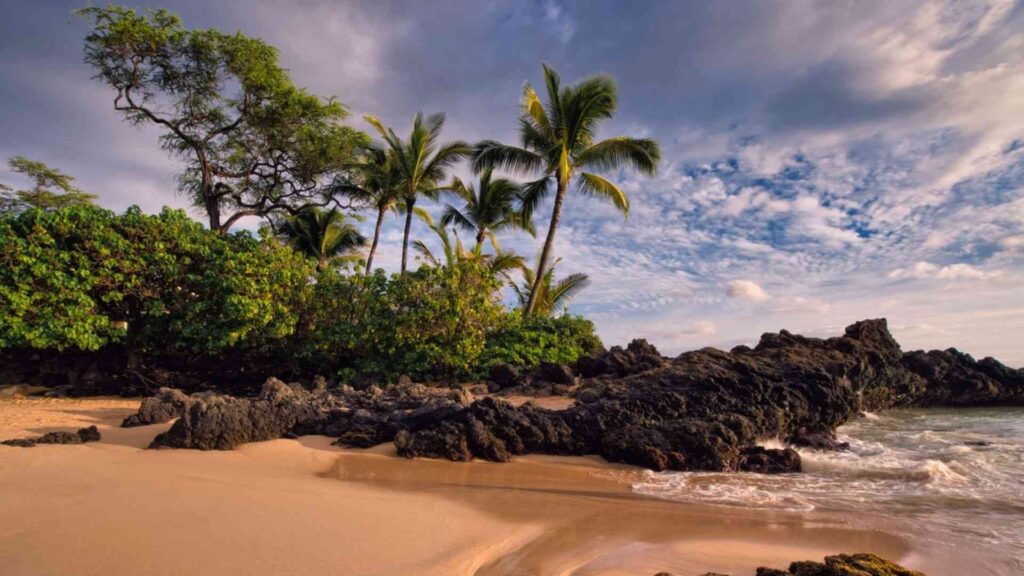 sunset picture from cove beach on Maui in Makena with rocks and ocean crashing up on shore
